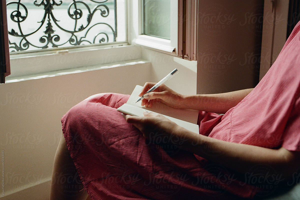 A woman writing her notes in a notepad.