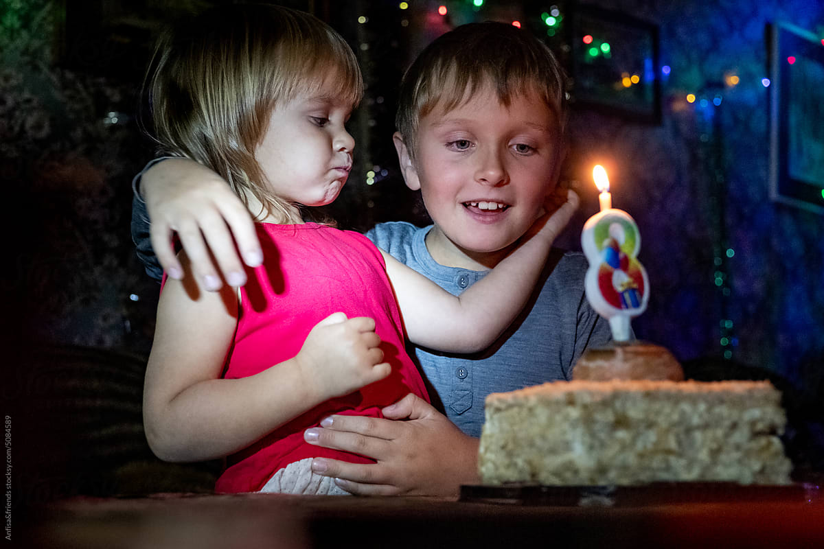 sincere kids looks at the candle on birthday cake