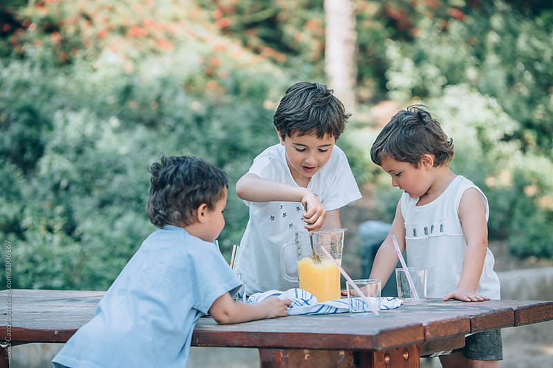 Children sharing a orange juice at the park