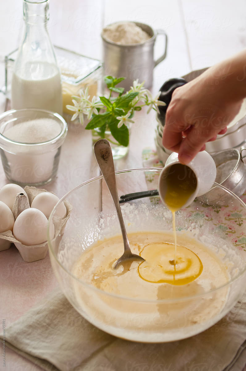 pouring  melted butter in a bowl with flour, eggs and milk