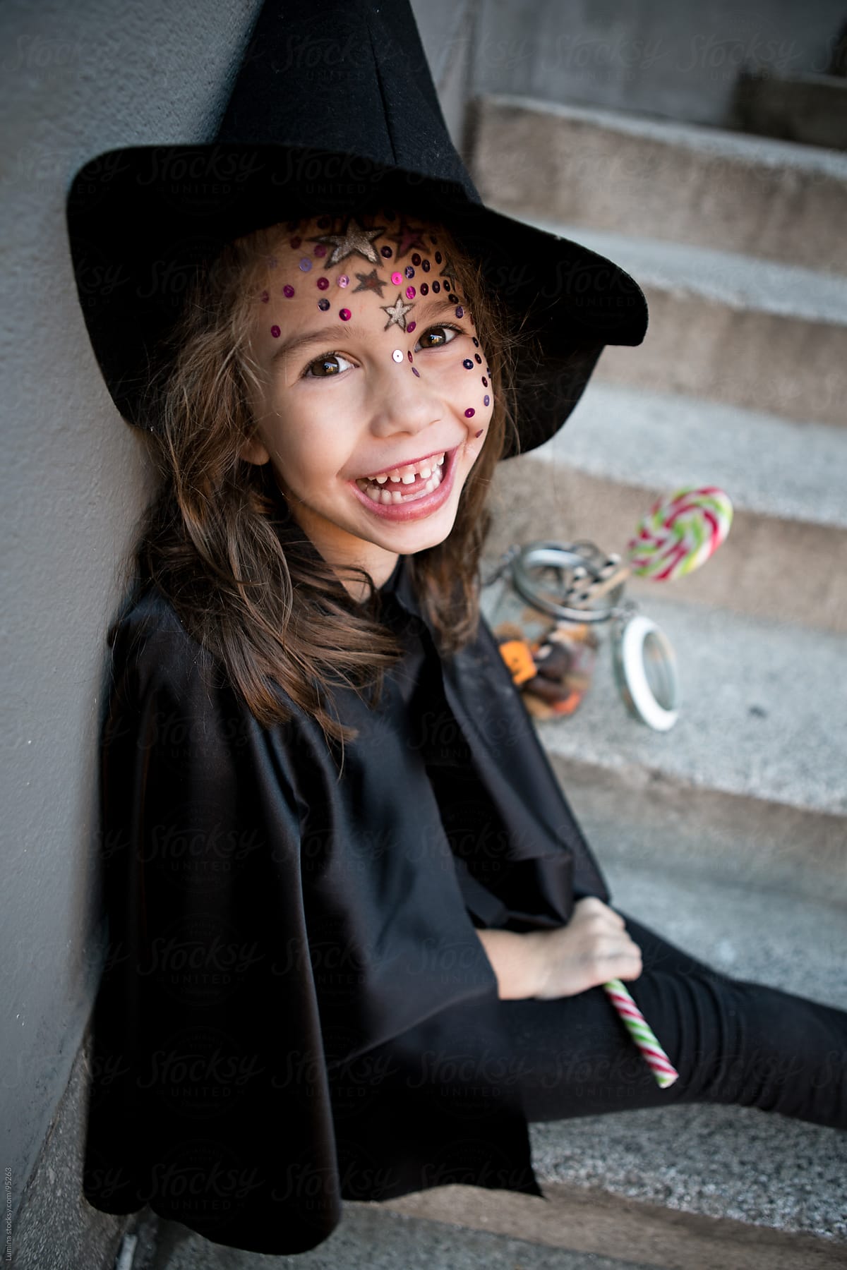 Girl in a Witch Costume With Halloween Treats