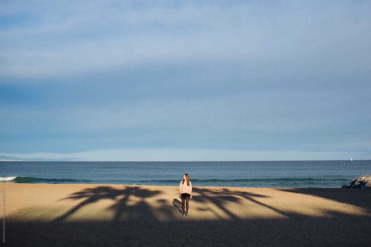 Young woman in the shadows of the palm trees on the beach