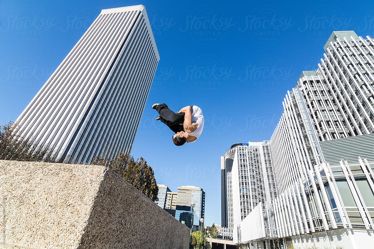 Man doing a somersault in the air during a parkour training in a city