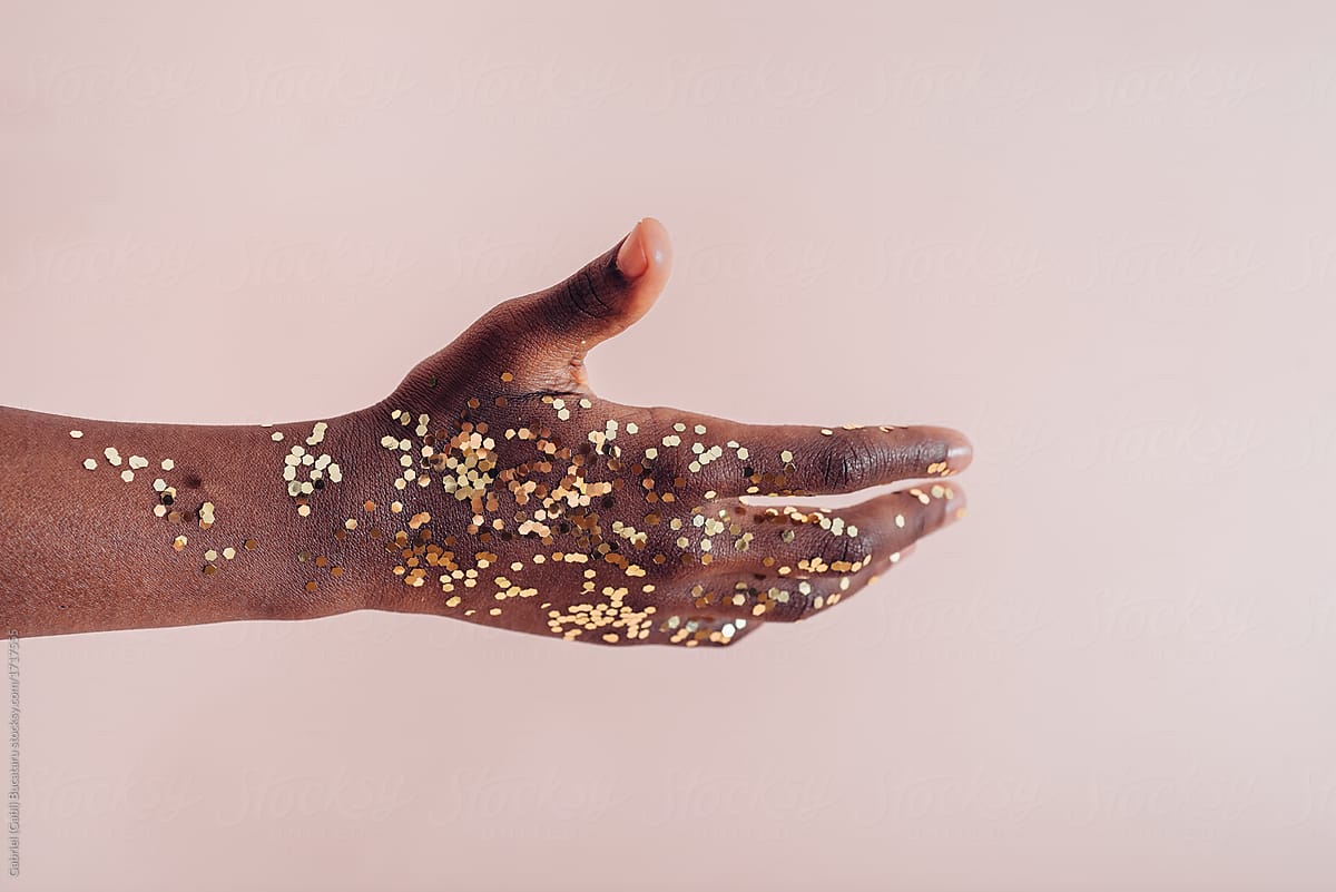 Hand of a black girl with sparkly golden confetti