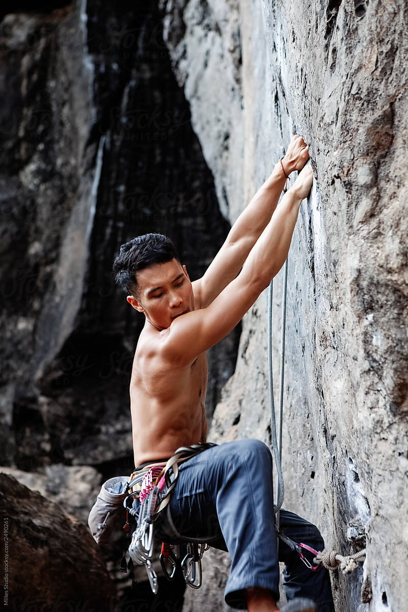 Strong ethnic man climbing rock