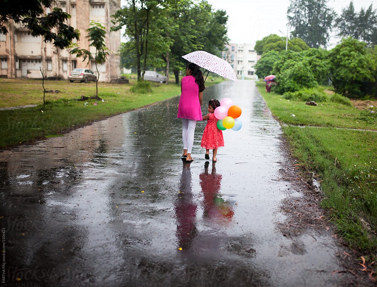 Elder sister walking with younger daughter in monsoon