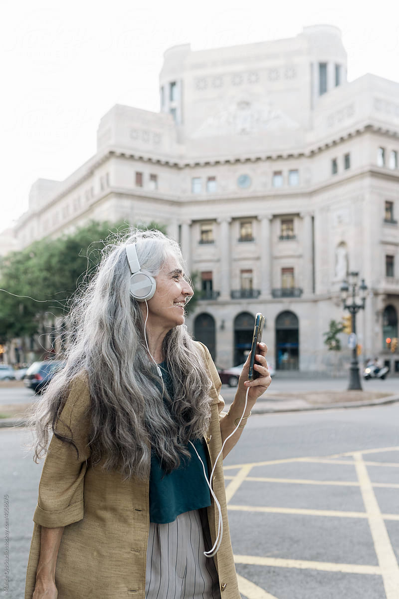 Grey-haired woman listening to music and dancing