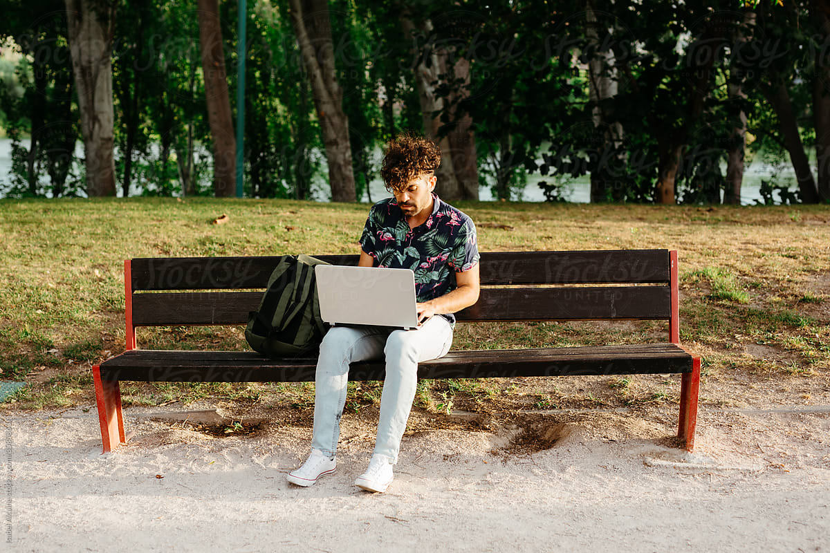 Portrait of a young boy on a park bench with his computer and backpack
