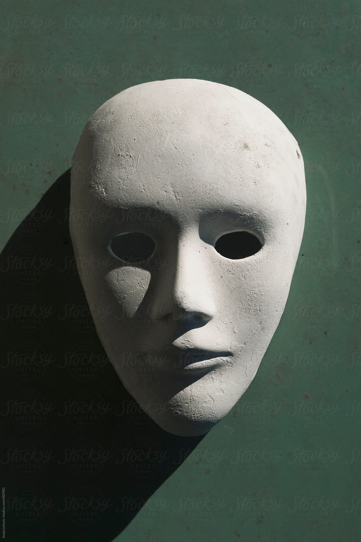white human face mask with a shadow on a green background