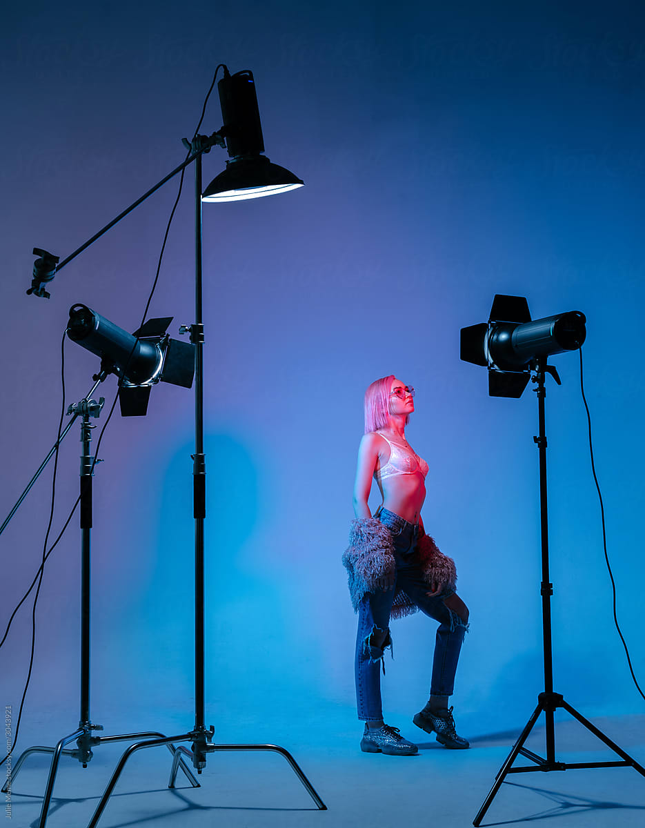 The girl with pink hair in a color light at the studio with light equipments