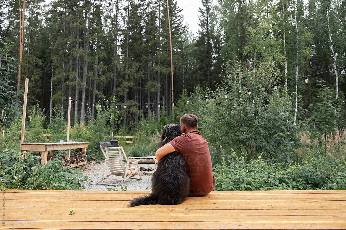 Man with dog admiring forest from terrace