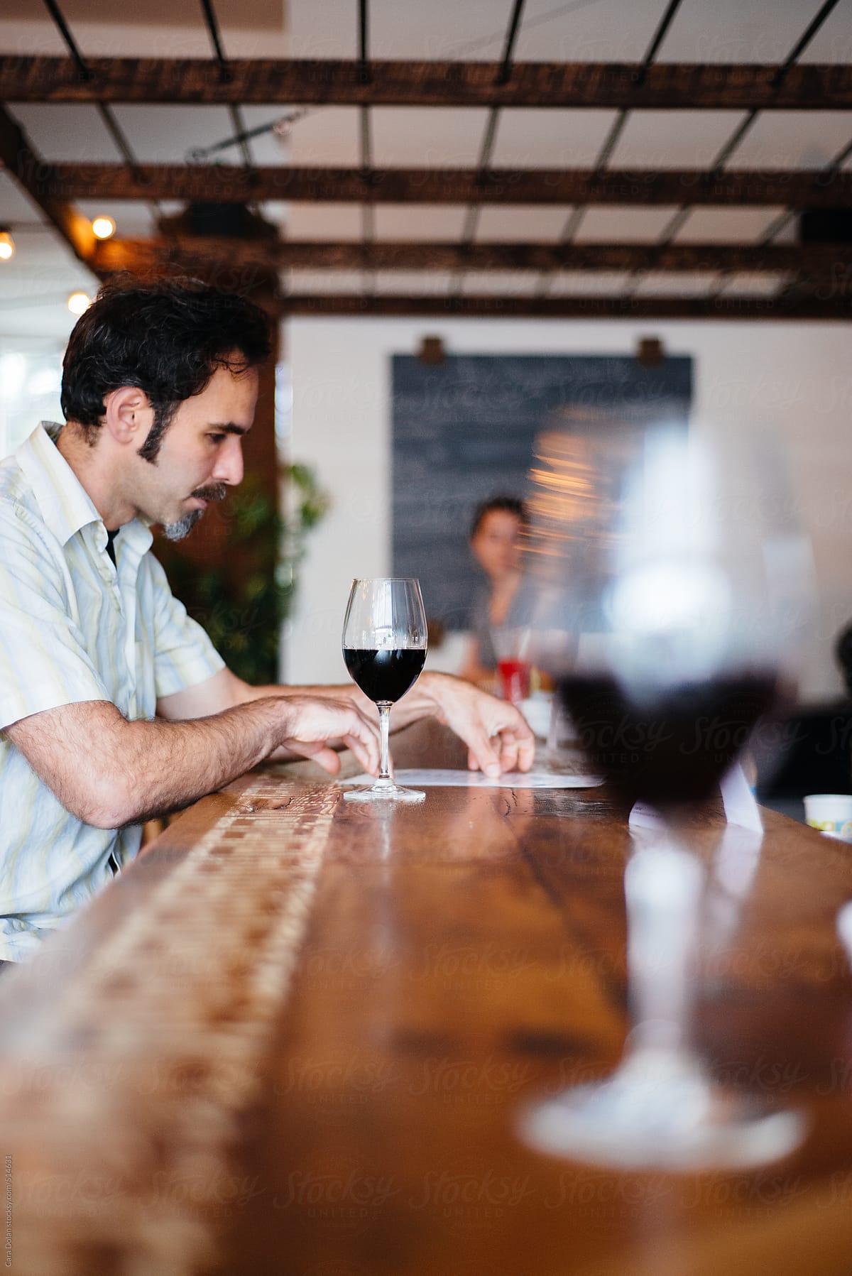 Man with glass of red wine looks at menu in a restaurant