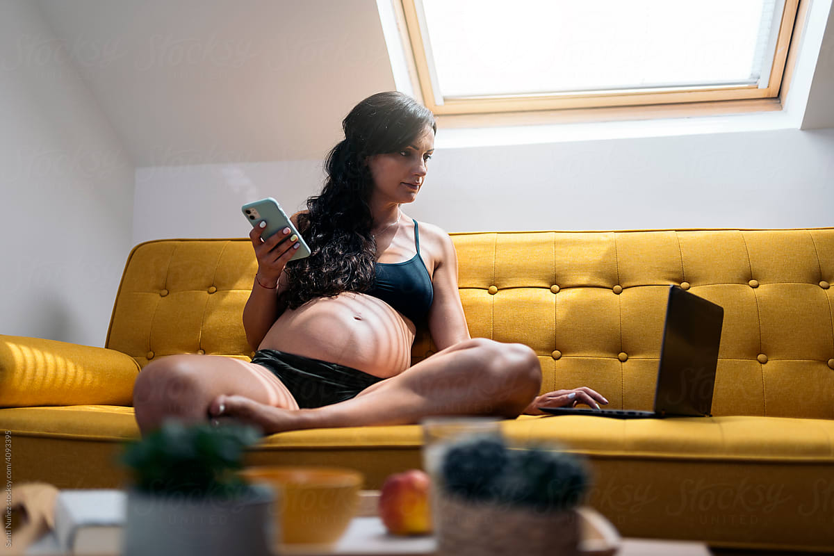 Pregnant woman working on her laptop and holding a mobile phone