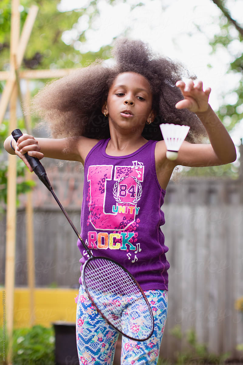 Young girl serving a badminton birdie