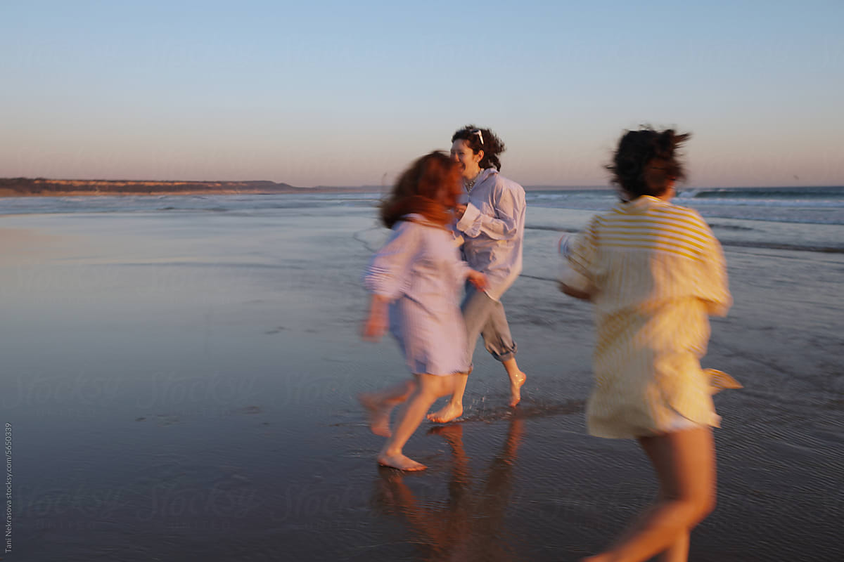 Three young female friends running by the ocean. Friendship