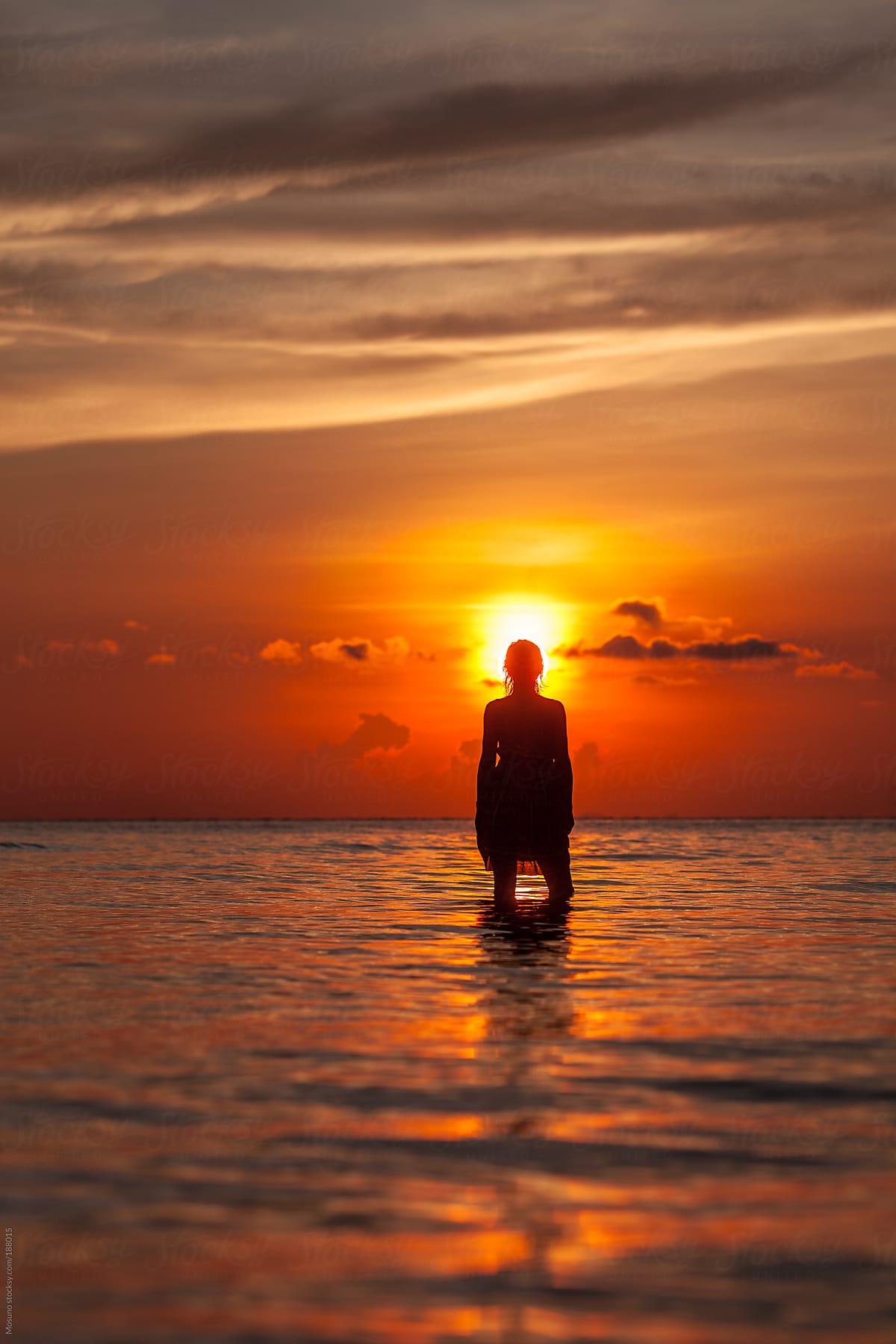 Female Silhouette Standing In A Shallow Water At Sunset Del