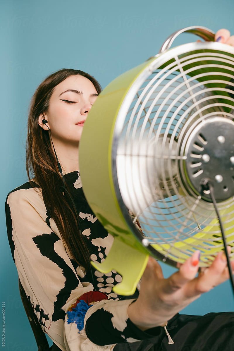 A young woman is chilling with a green fan in her hands