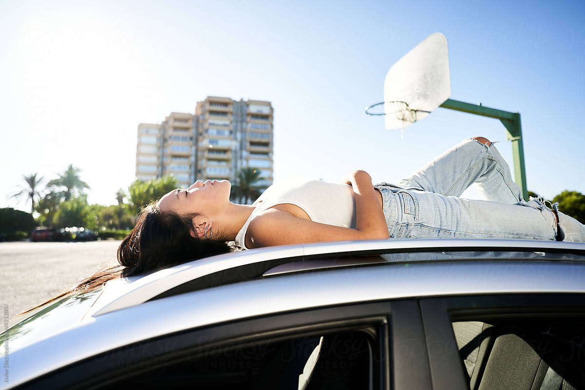 Young woman lying on SUV car