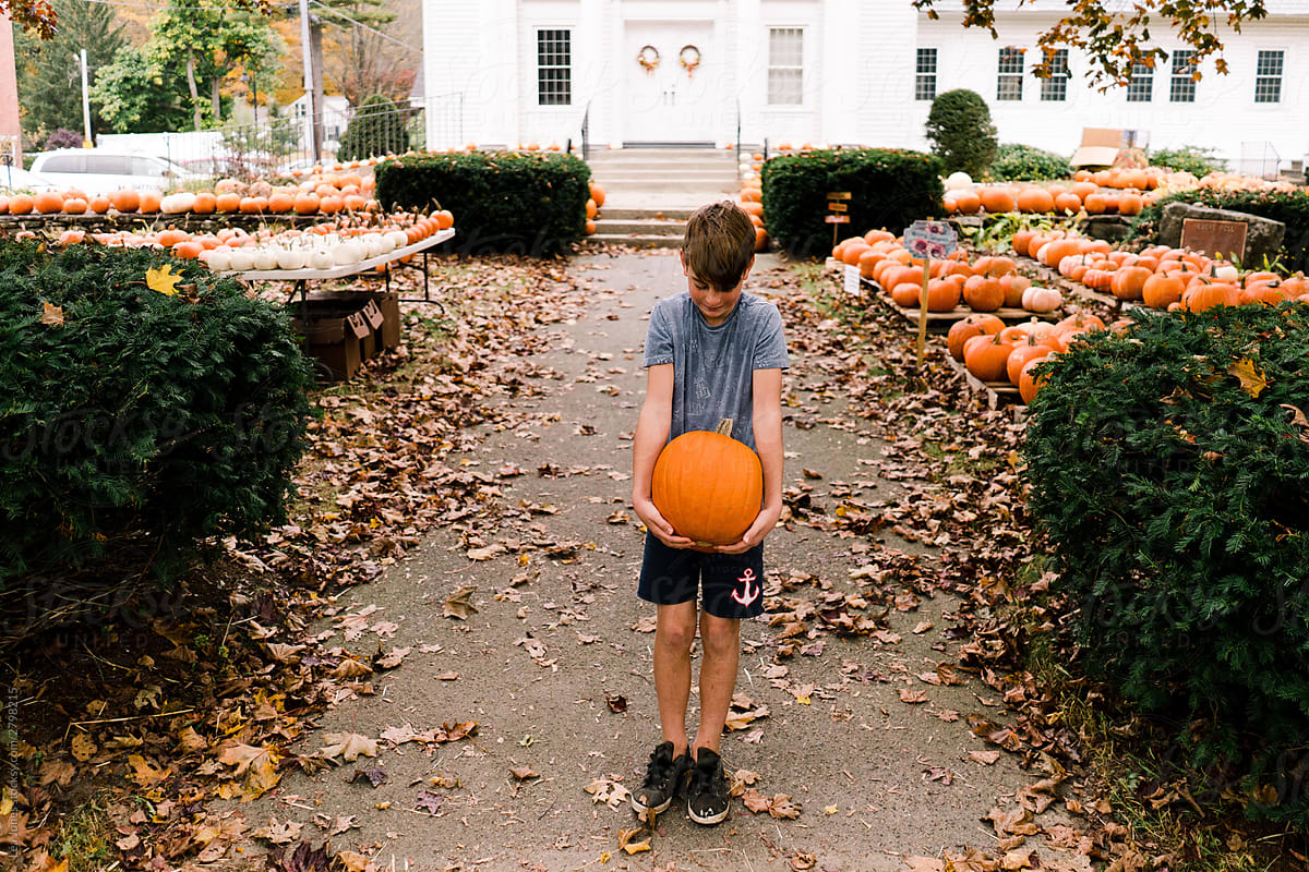 boy in front of church with pumpkin