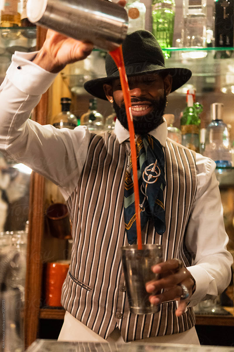 Happy black bartender mixing cocktail