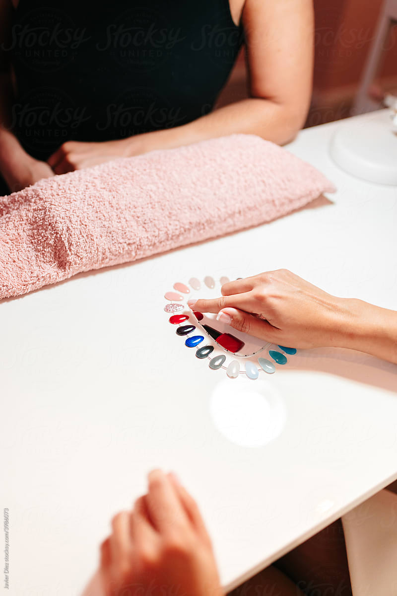 Woman showing nail color to manicurist