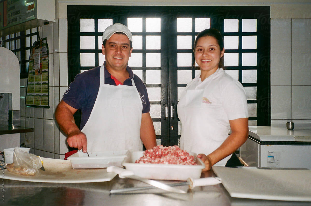 Couple of butchers proudly working on handmade sausage production