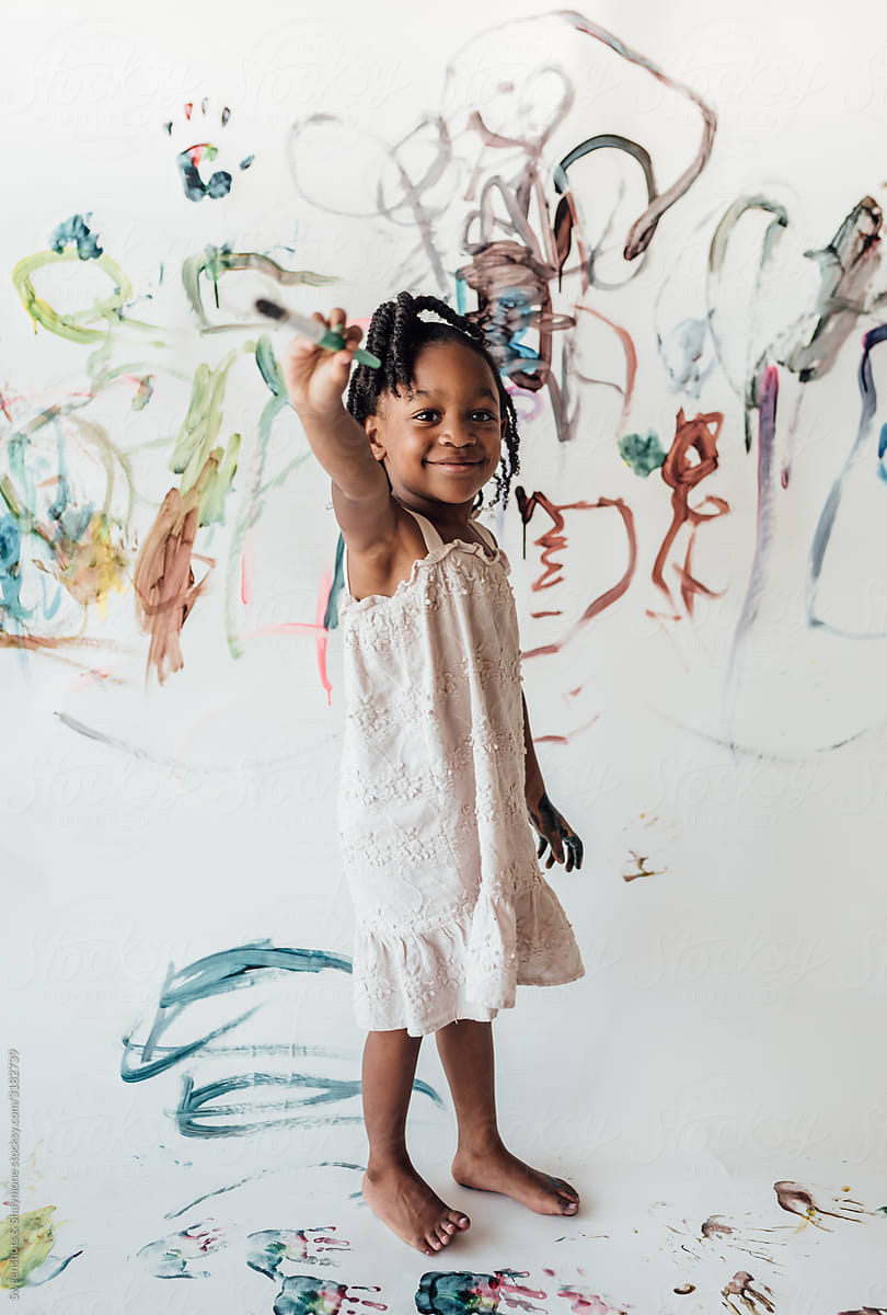 Little girl painting with washable markers on a large paper sheet