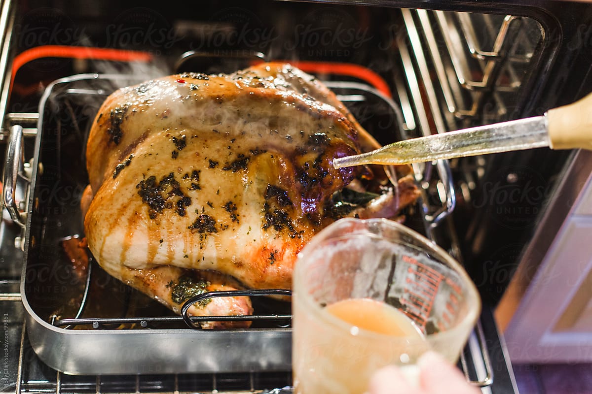 Steam rises off a turkey being basted in hot oven