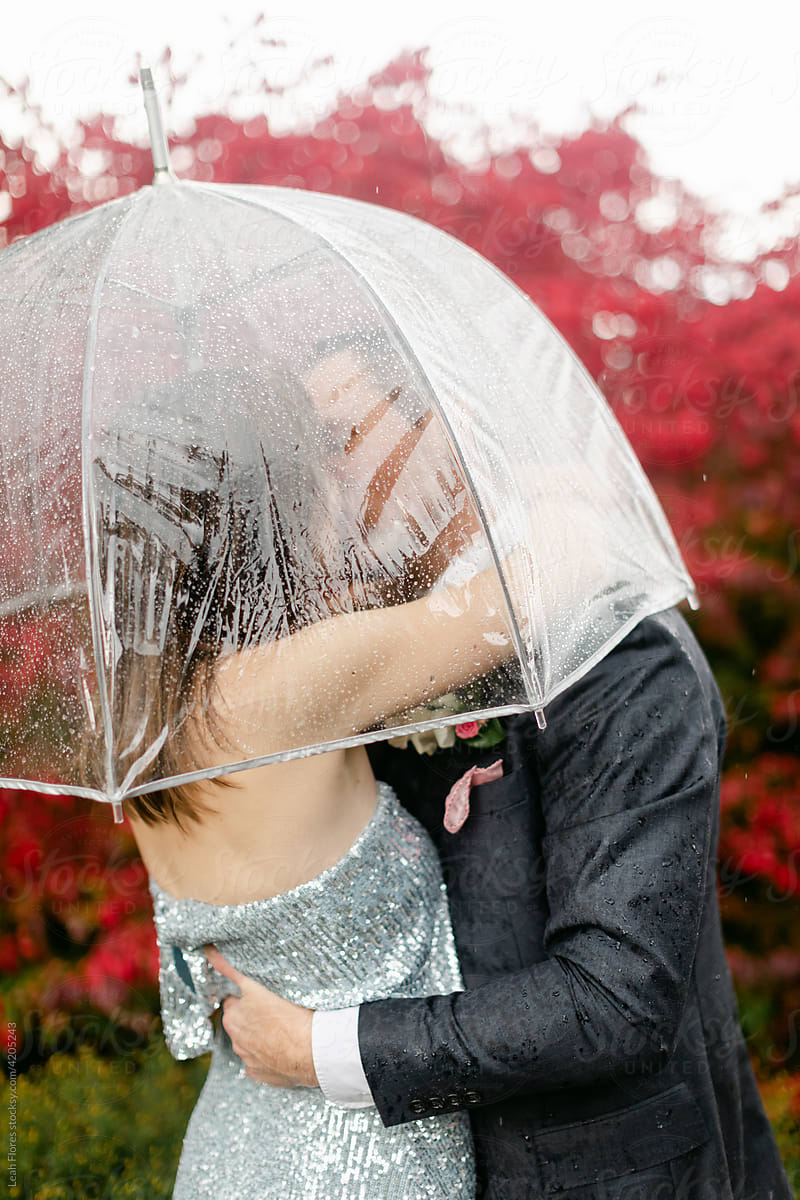 Bride and Groom Embrace and Kiss in the Rain