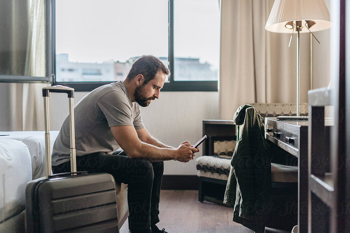 Man texting message on smartphone in hotel room