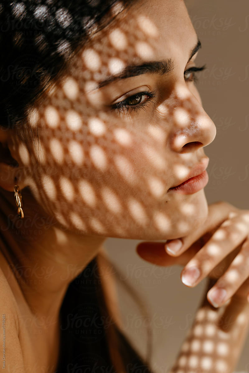 Crop pondering woman with sunlight shades through sieve