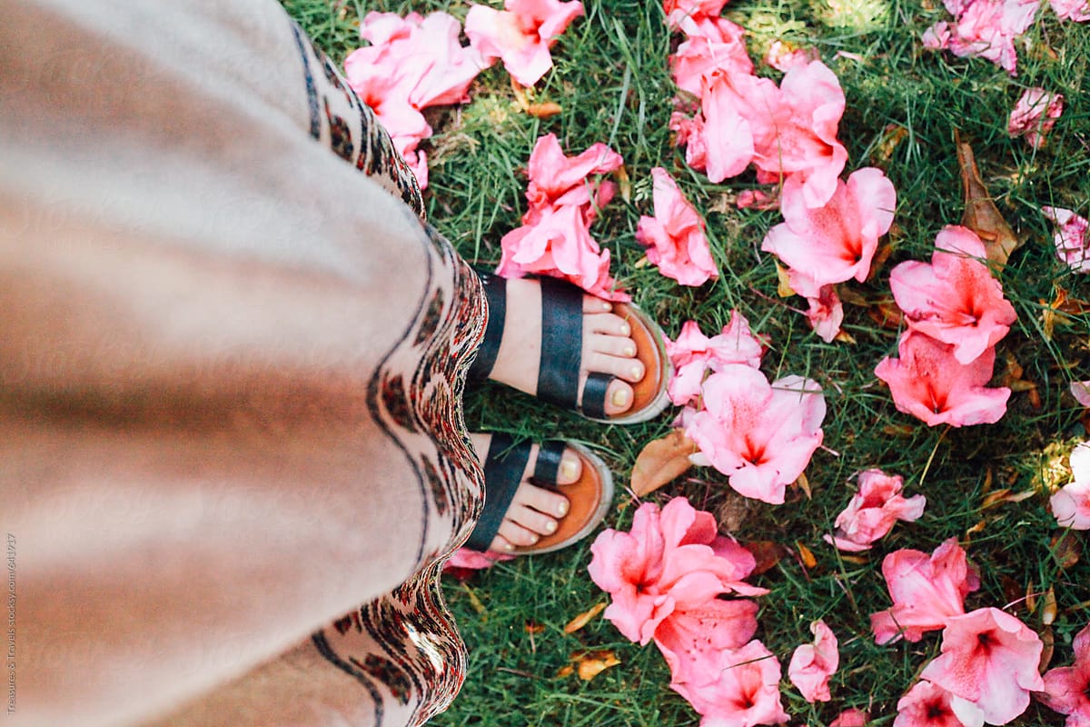 woman\'s feet and flower petals shot from above