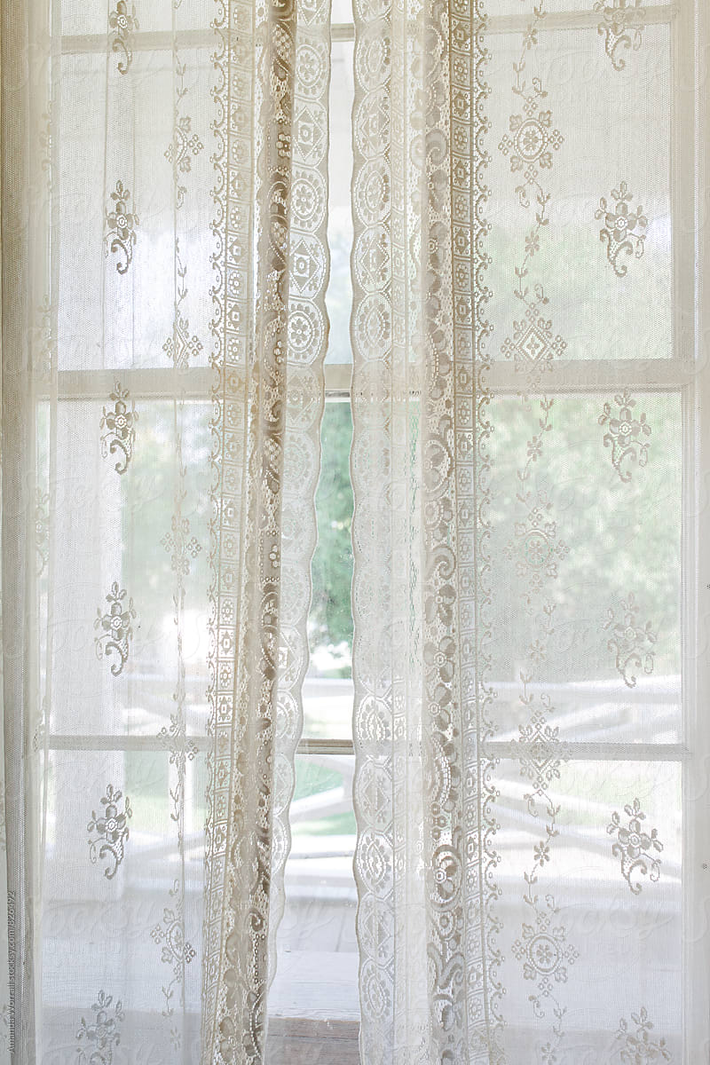 Delicate lace curtains covering a window in summer