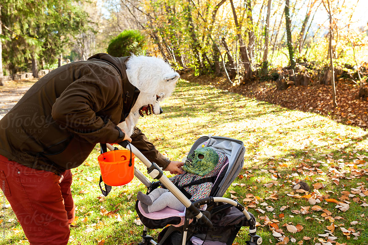 Father with his baby on stroller wearing Halloween masks
