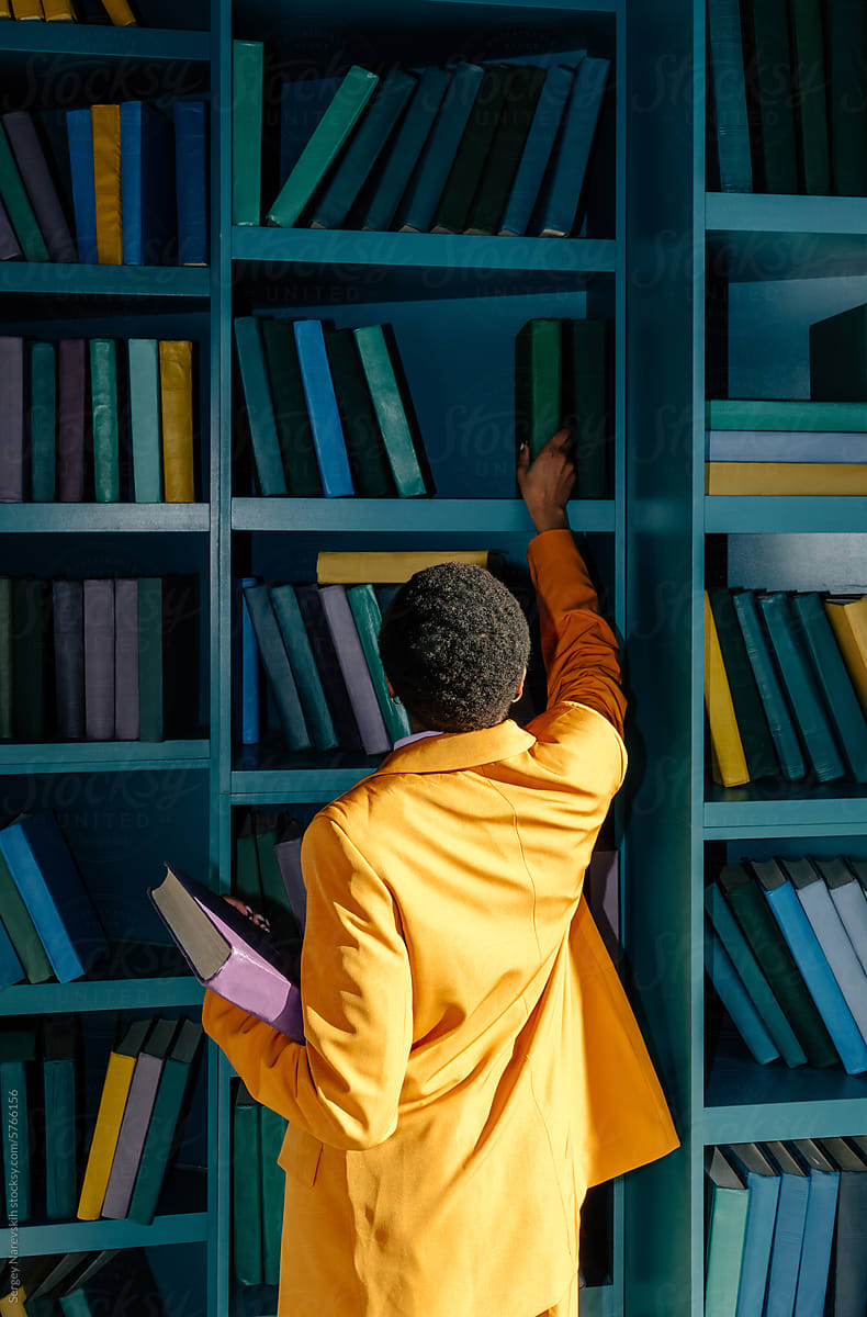 Anonymous female in yellow outfit choosing book
