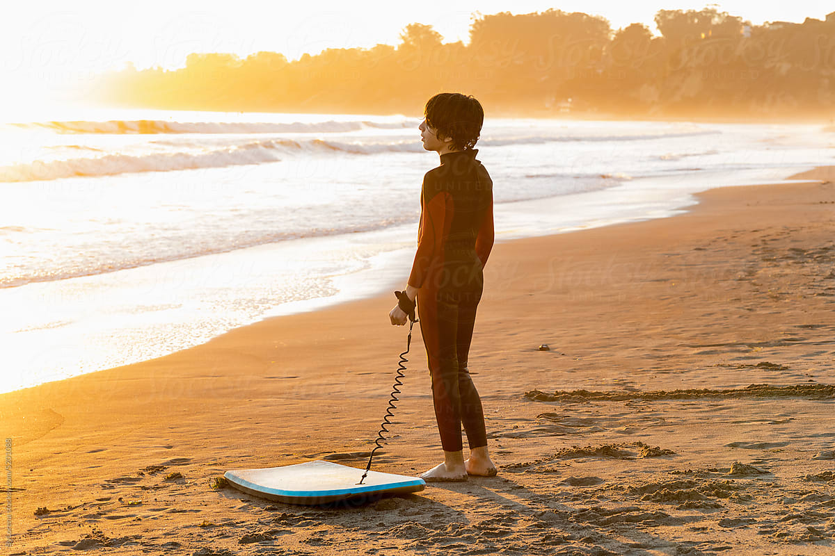 Teenager with surfboard looking at the sea