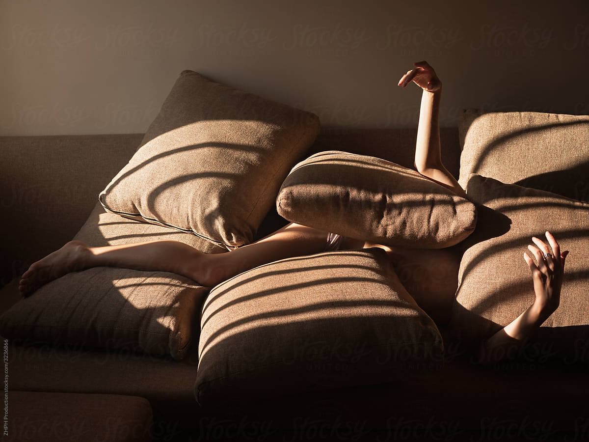 Woman on sofa covered by pillows