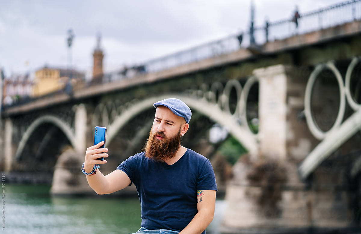 Man taking selfie on cellphone while sitting near of river