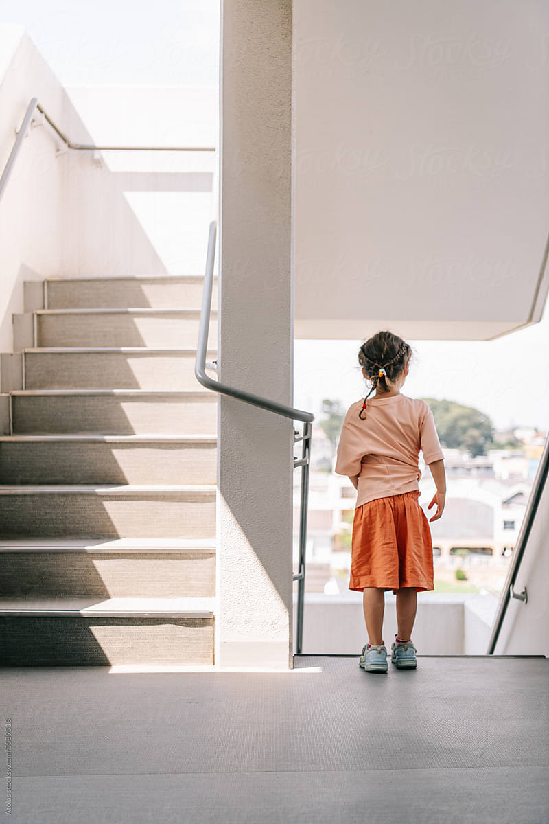 Small girl waiting by staircase