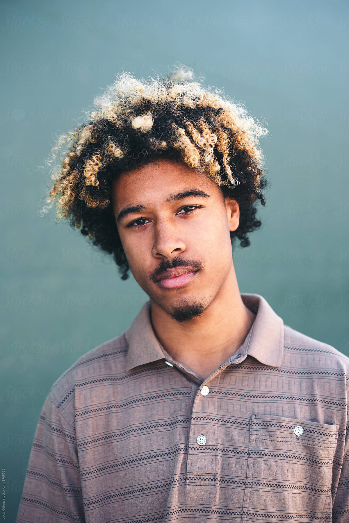 serious mixed race teenager with blonde afro hair by lucas