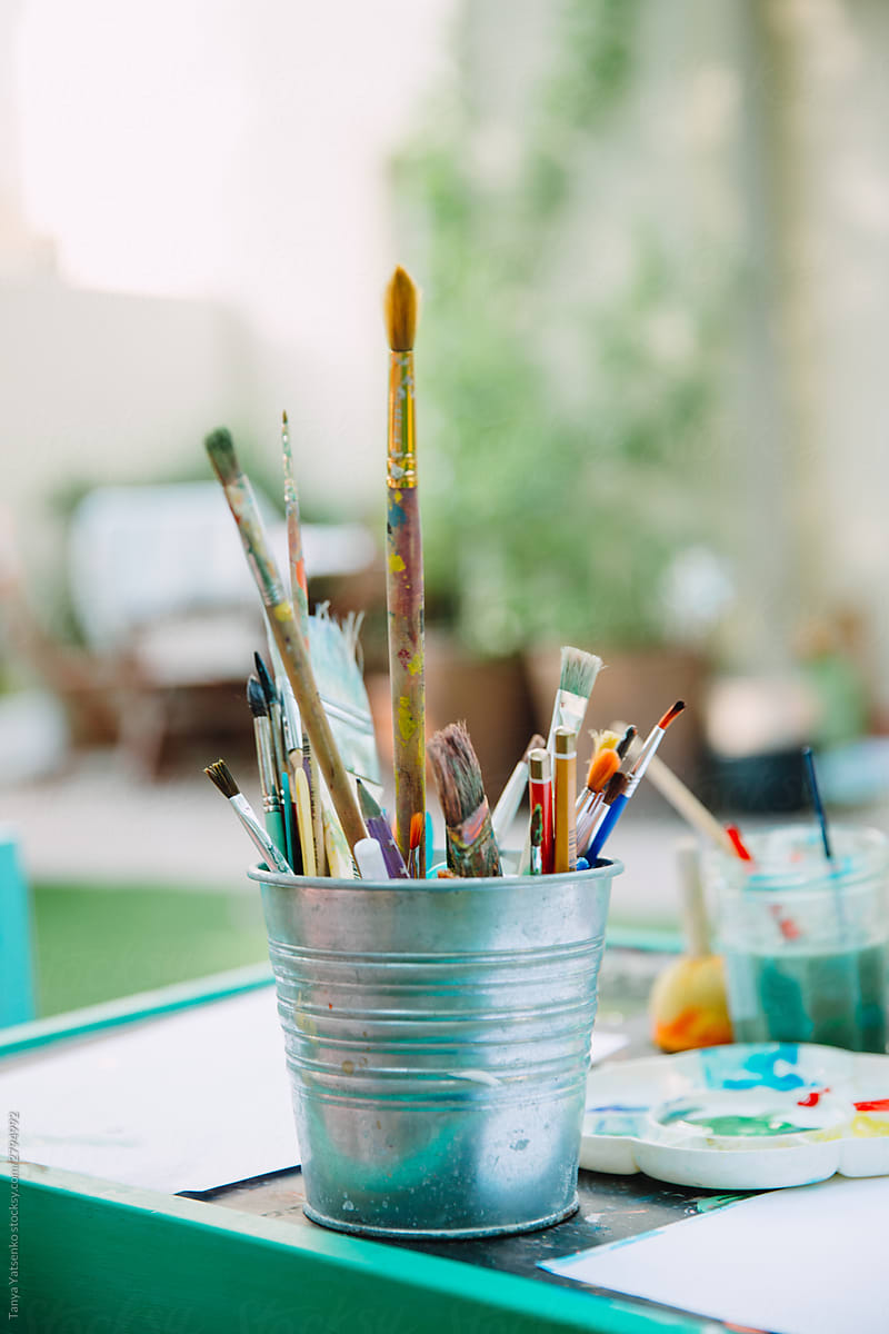 A bucket full of brushes and pencils on the table