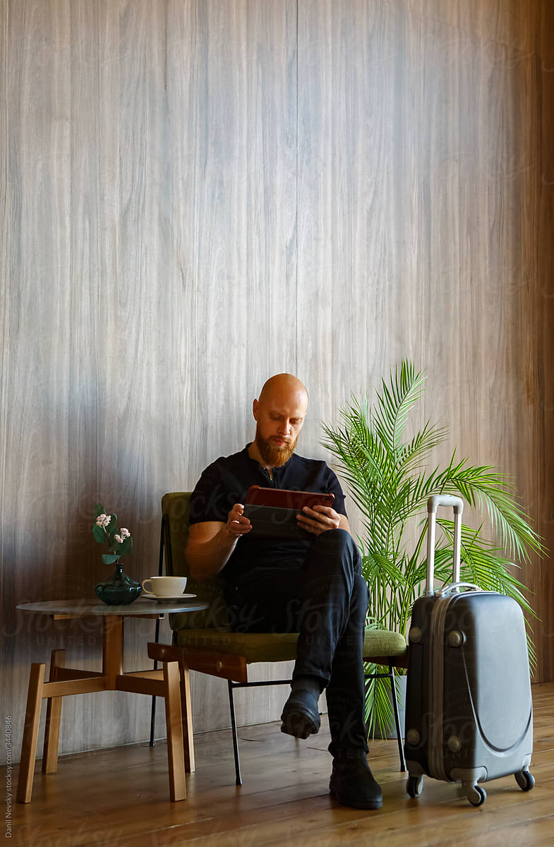 Male traveler browsing tablet in lobby