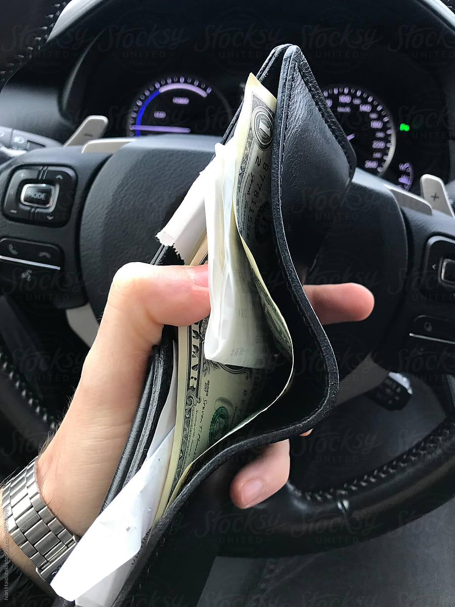 Wallet with money US Dollars and receipts inside car in hand - UGC