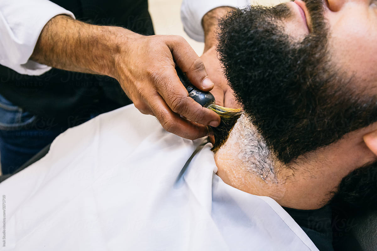 Anonymous barber applying foam to shave man