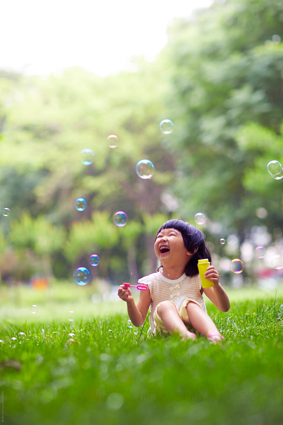 happy little  girl playing with soap bubble in the park