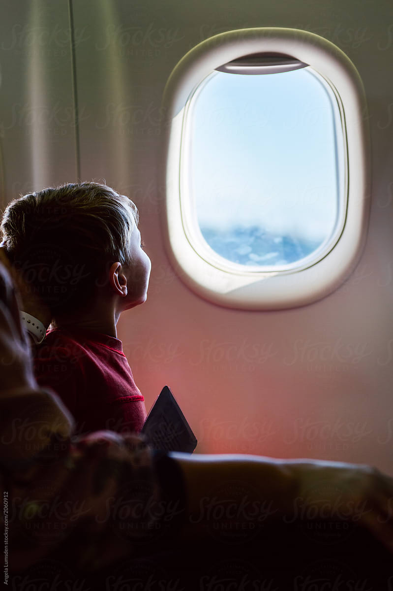 Small Child Looking Excitedly Out An Airplane Window by Angela Lumsden