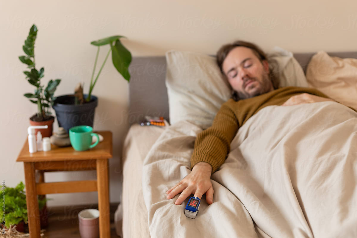 sick man measures saturation in bed lying down