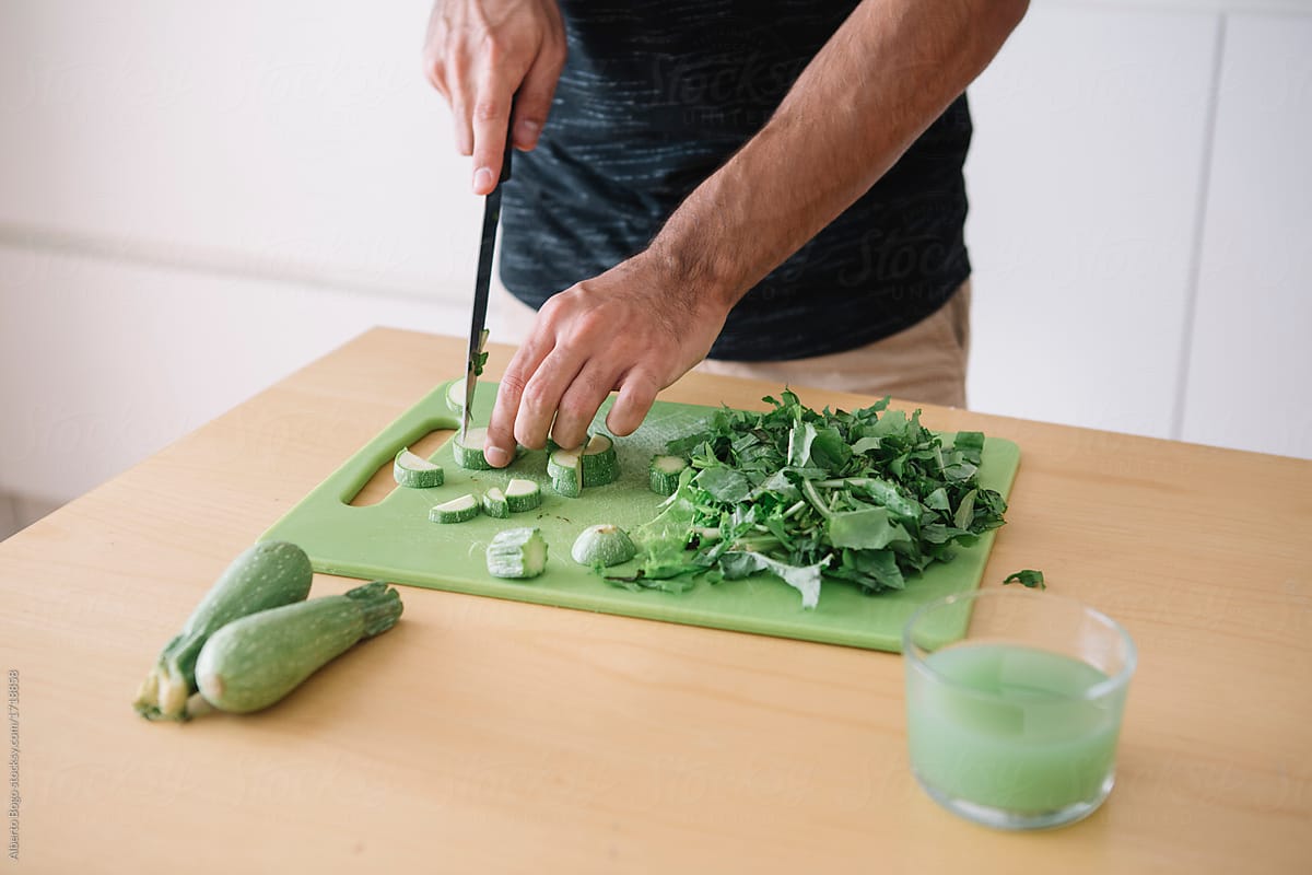 Man cutting green on kitchen
