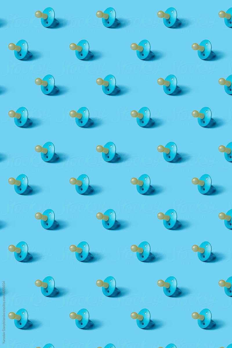 Pattern of baby soothers on blue background.