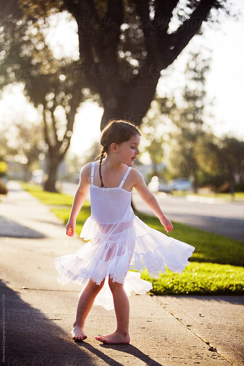 Young Girl Wearing White Slip Dress Twirling On Sidewalk By Dina Marie 